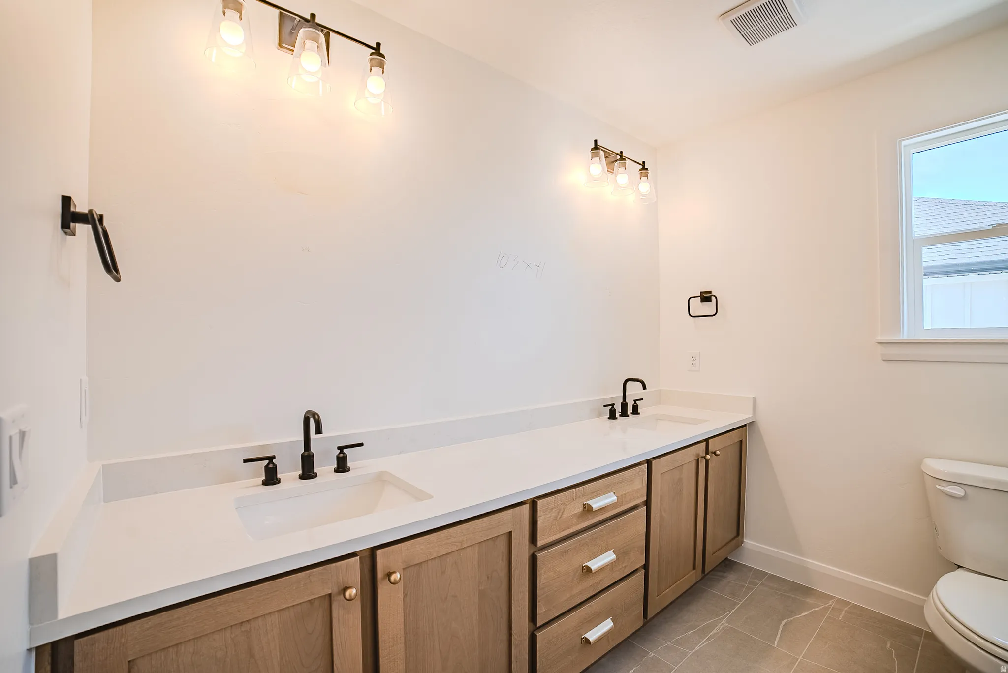 Dual vanity featuring light wood-finish cabinetry and white countertops