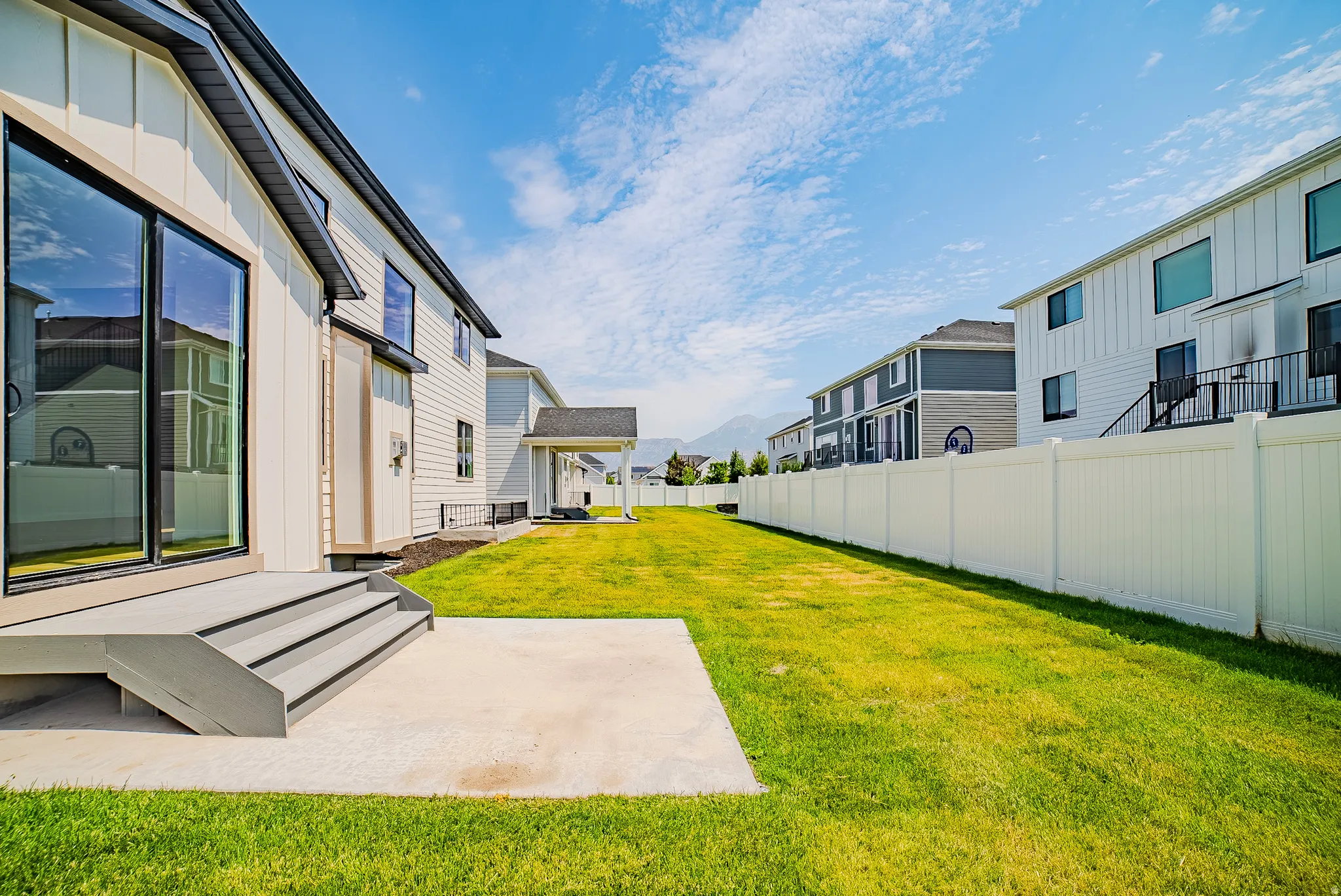 Expansive green lawn with a white privacy fence