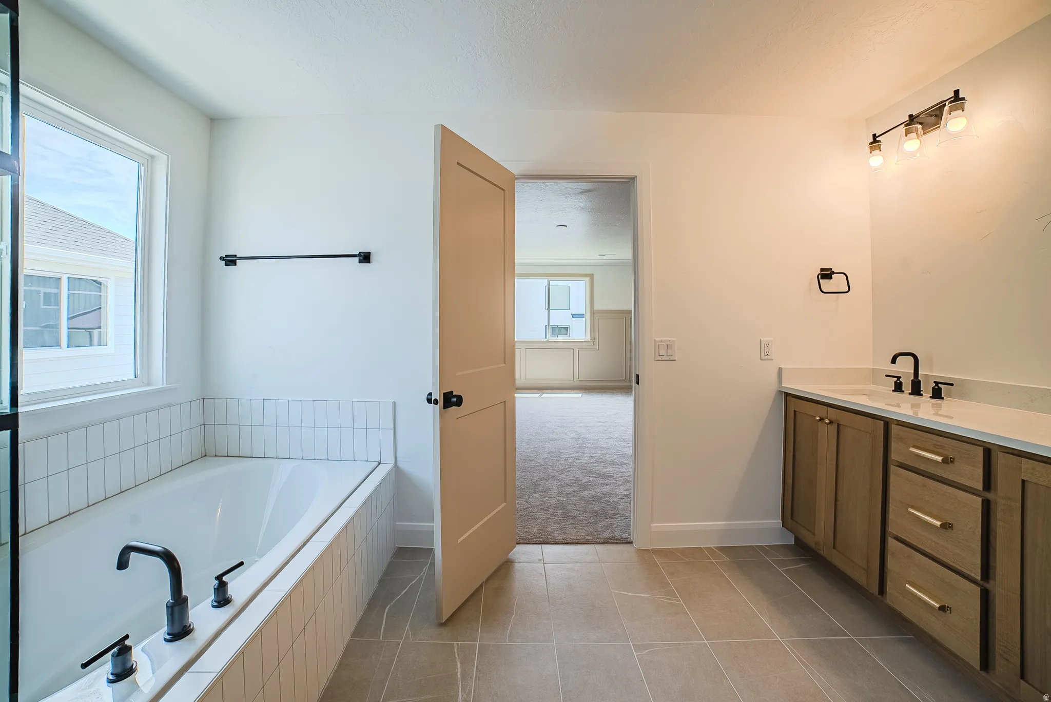 Bathroom featuring a built-in tub with matte black fixtures, subway tile surround, and a large window