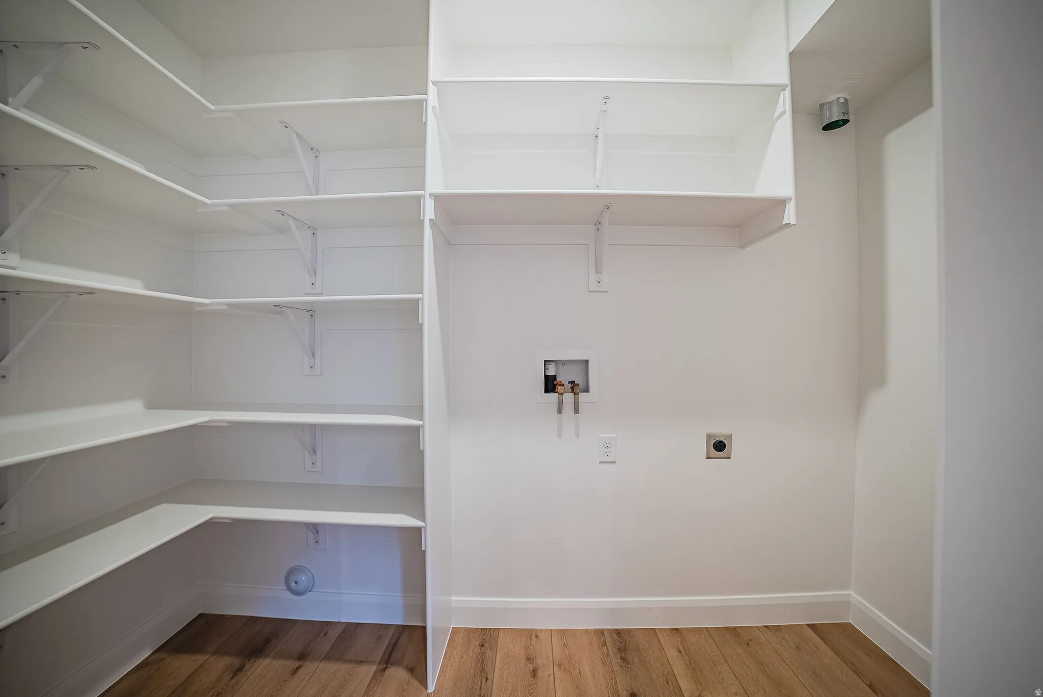 Utility area featuring white walls, wood-finish flooring, and white baseboards