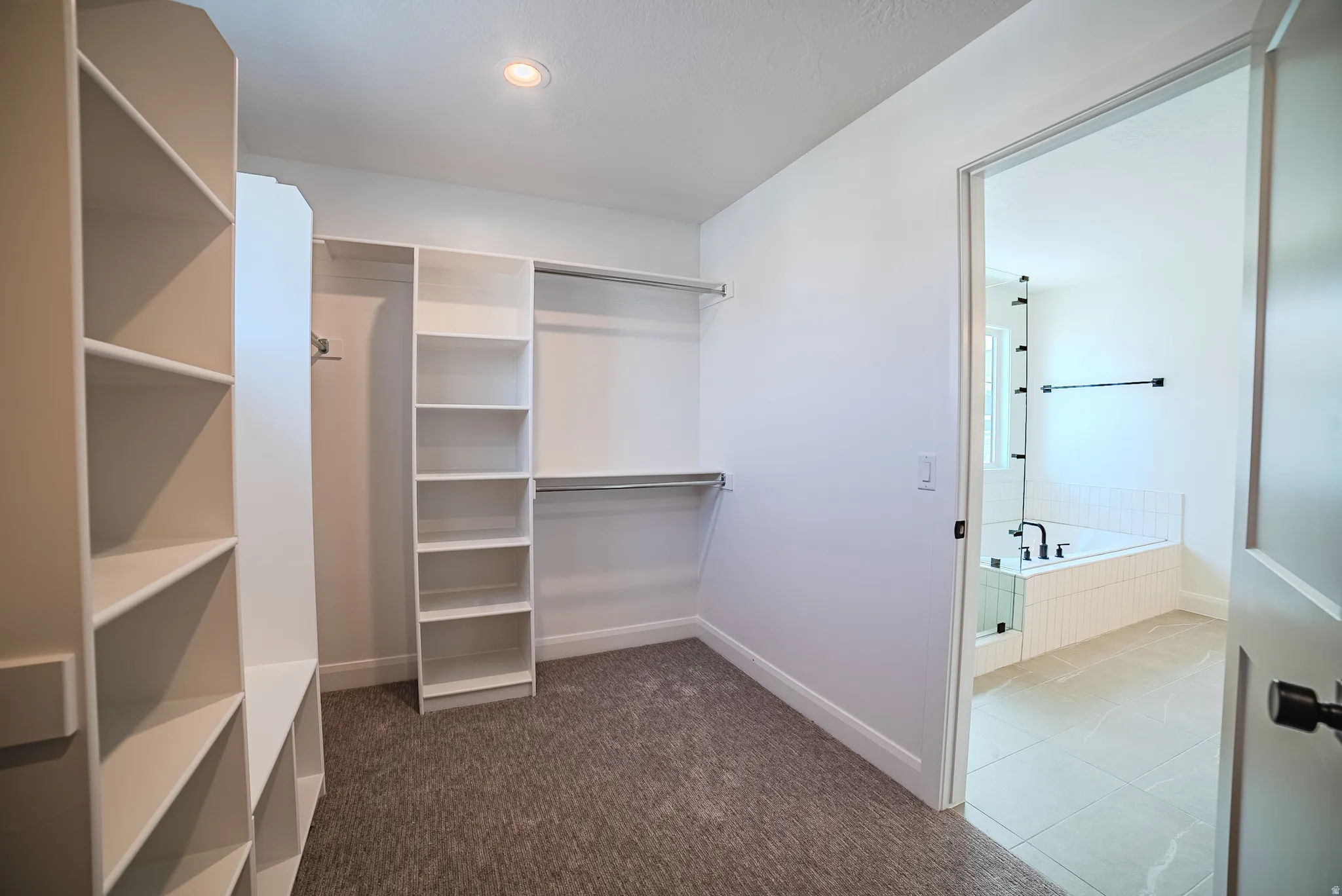 Walk-in closet with carpet flooring, recessed lighting, white built-in shelving, and hanging rods