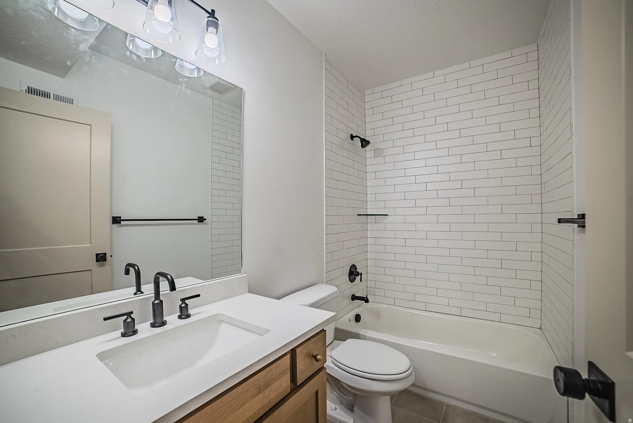 Bathroom featuring a single vanity with a white countertop and integrated sink, a wood-finish cabinet base, and a black faucet set