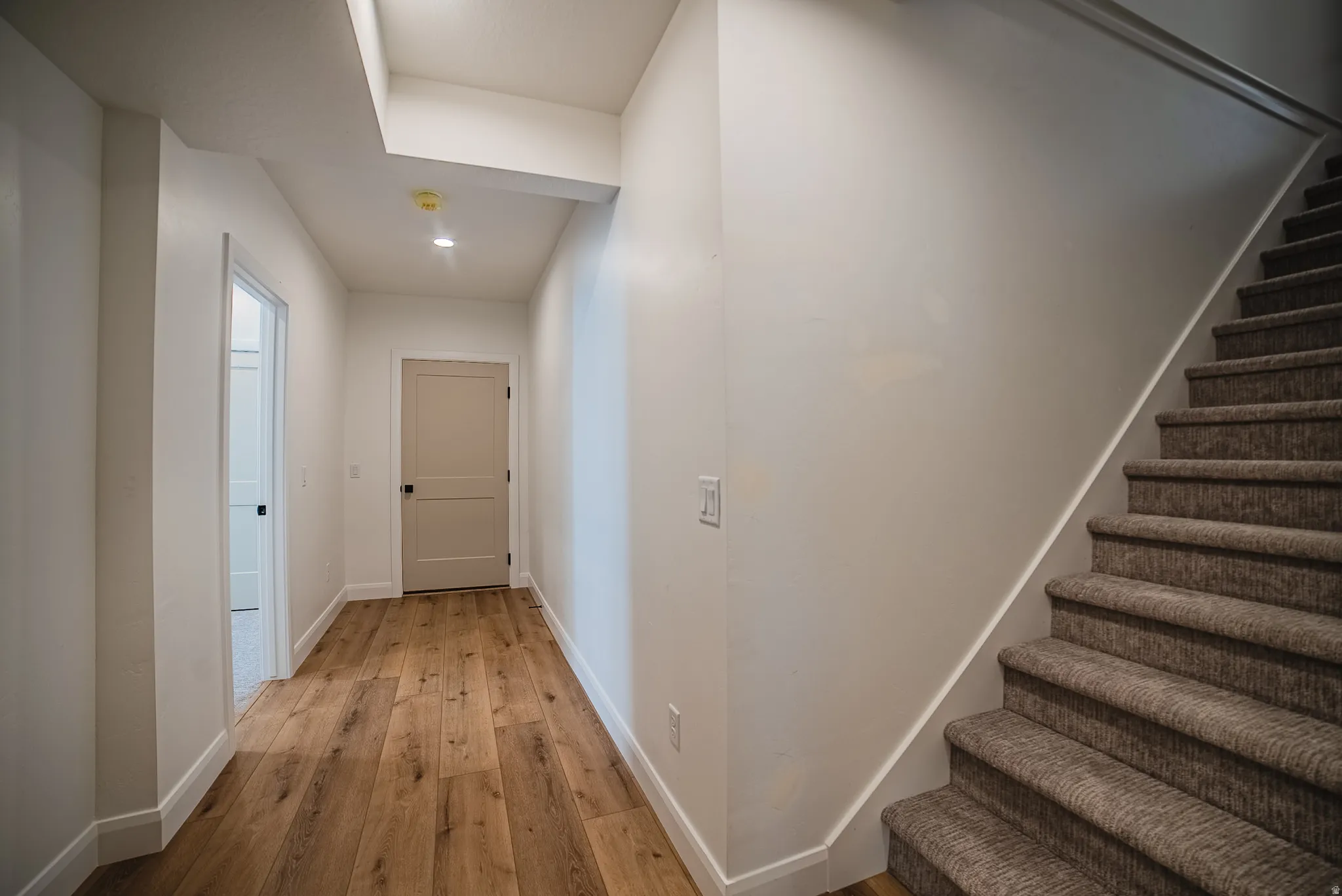 Entryway featuring wood-finish flooring, recessed lighting, white trim, and a carpeted staircase