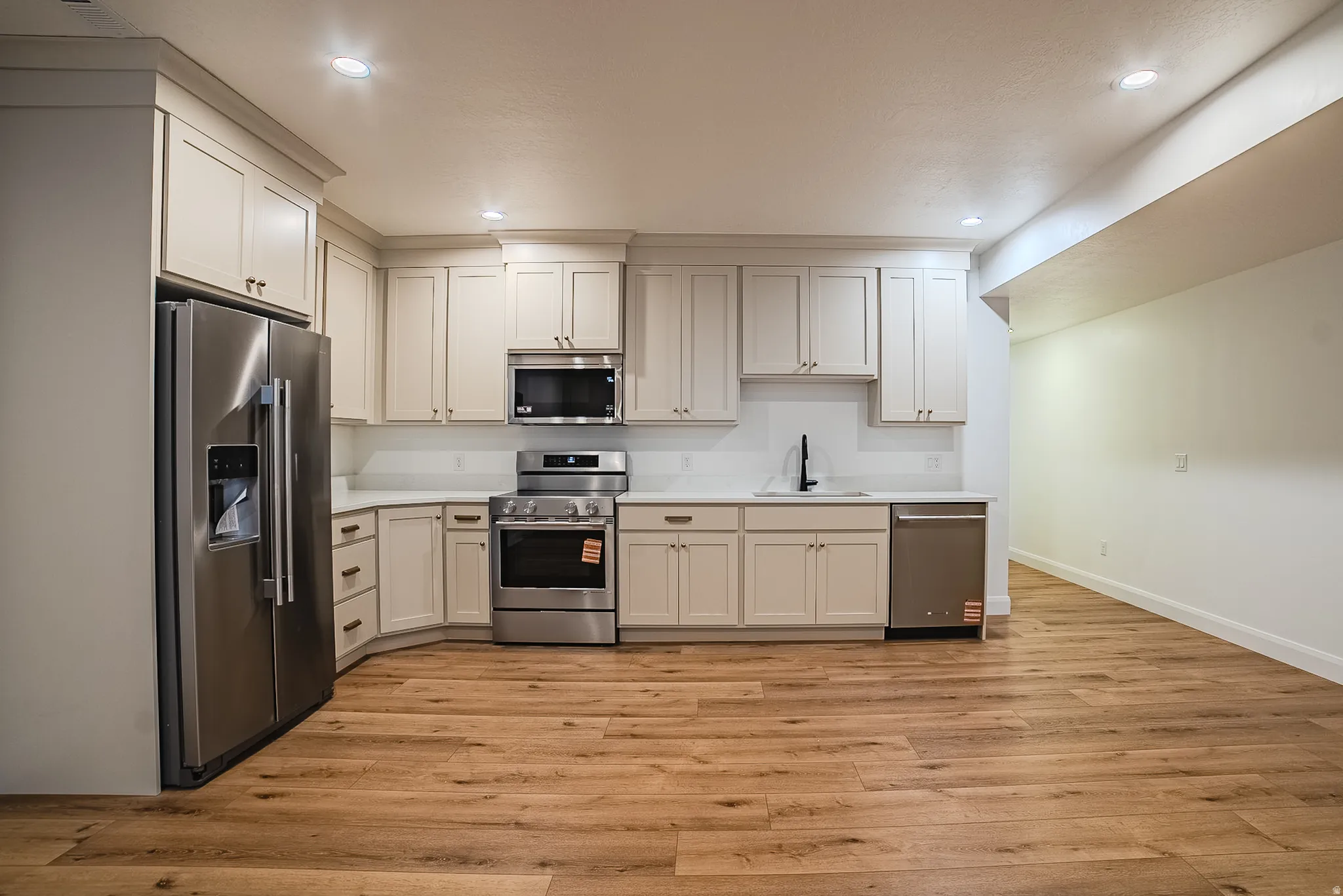 Kitchen featuring wood-finish flooring, recessed lighting, and stainless steel appliances including a refrigerator, range, microwave, and dishwasher