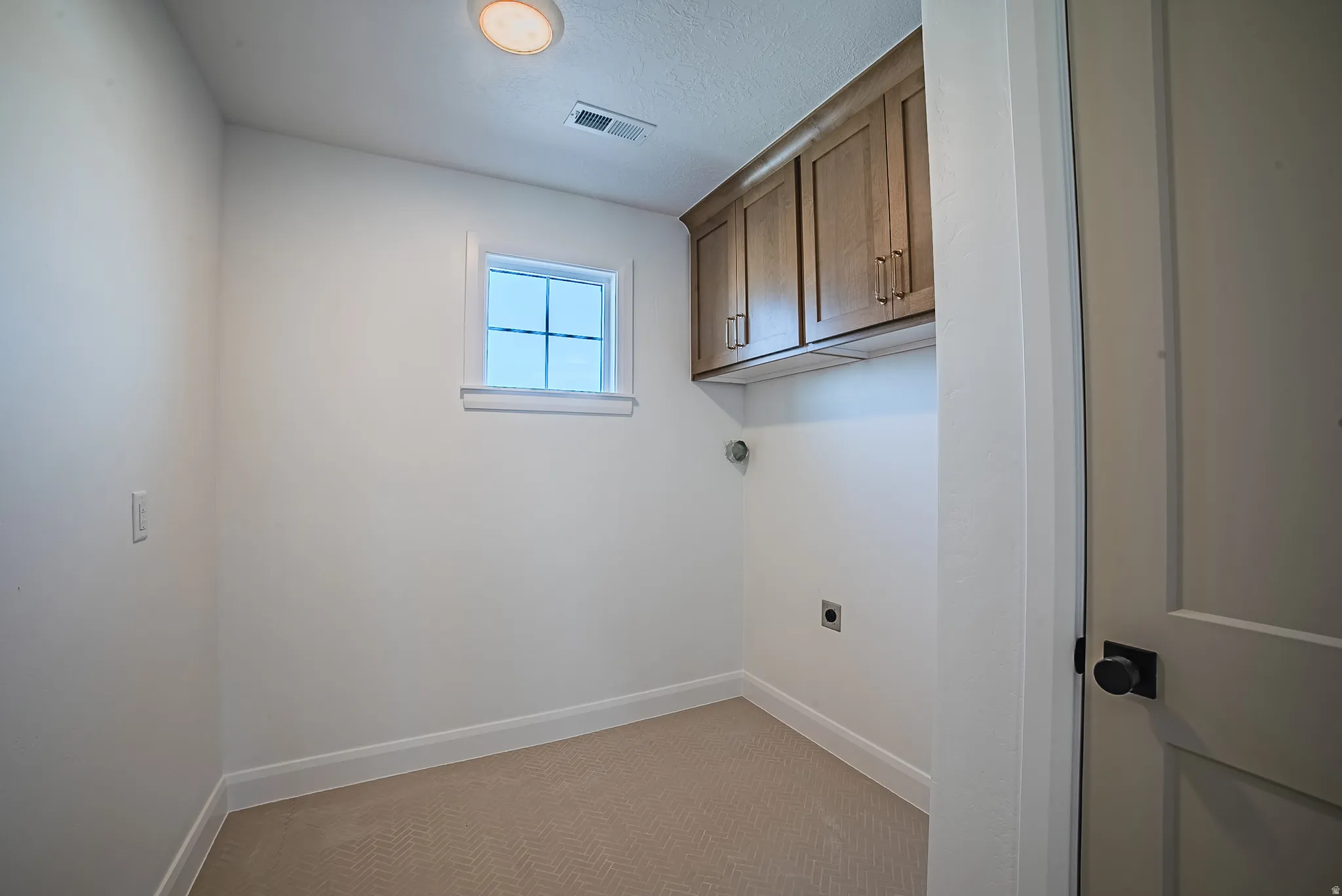 Dedicated utility space featuring overhead wood-finish cabinetry, a single window, recessed lighting, and herringbone pattern carpet flooring