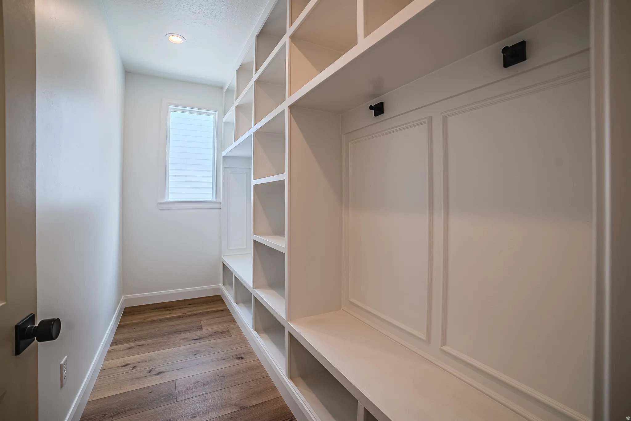 Built-in white cabinetry featuring multiple open shelves, integrated seating, and decorative wall paneling