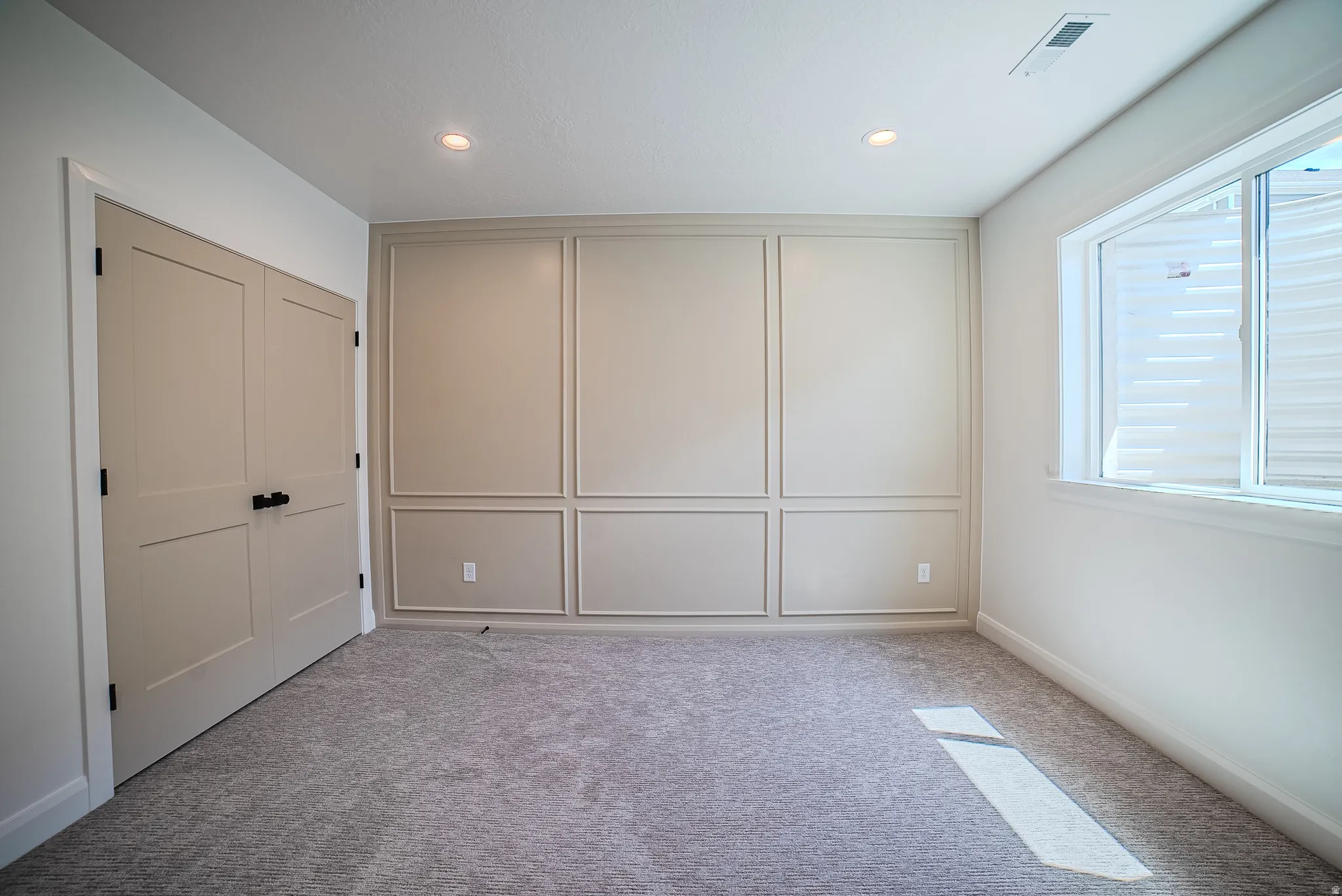 Room featuring wainscoting accent wall, recessed lighting, and grey carpet flooring