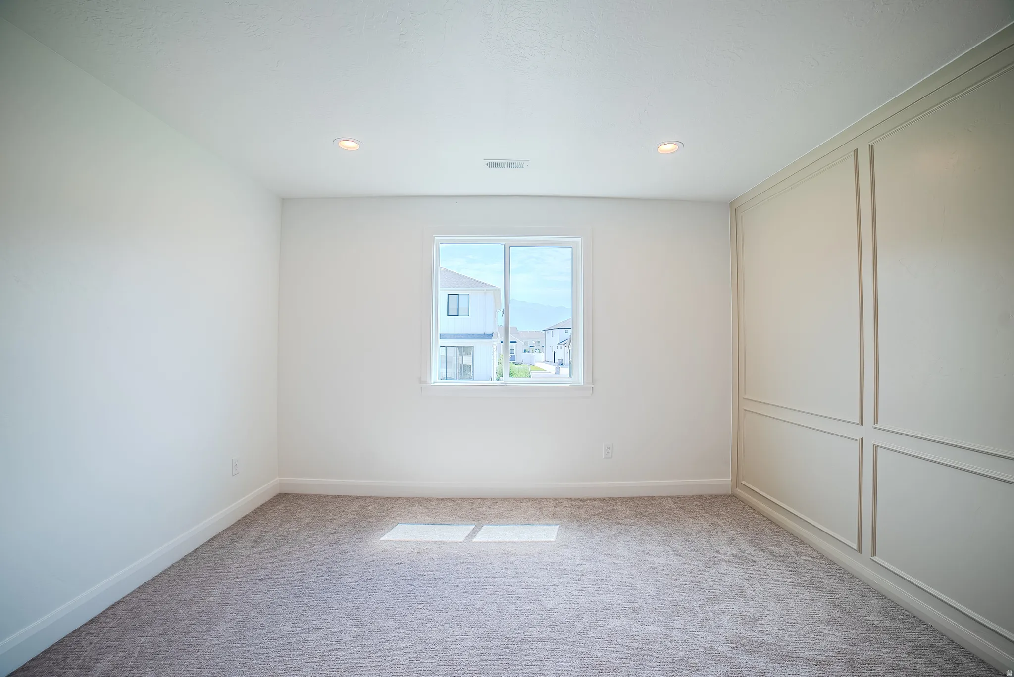 Interior room featuring a single window, recessed lighting, and a paneled accent wall