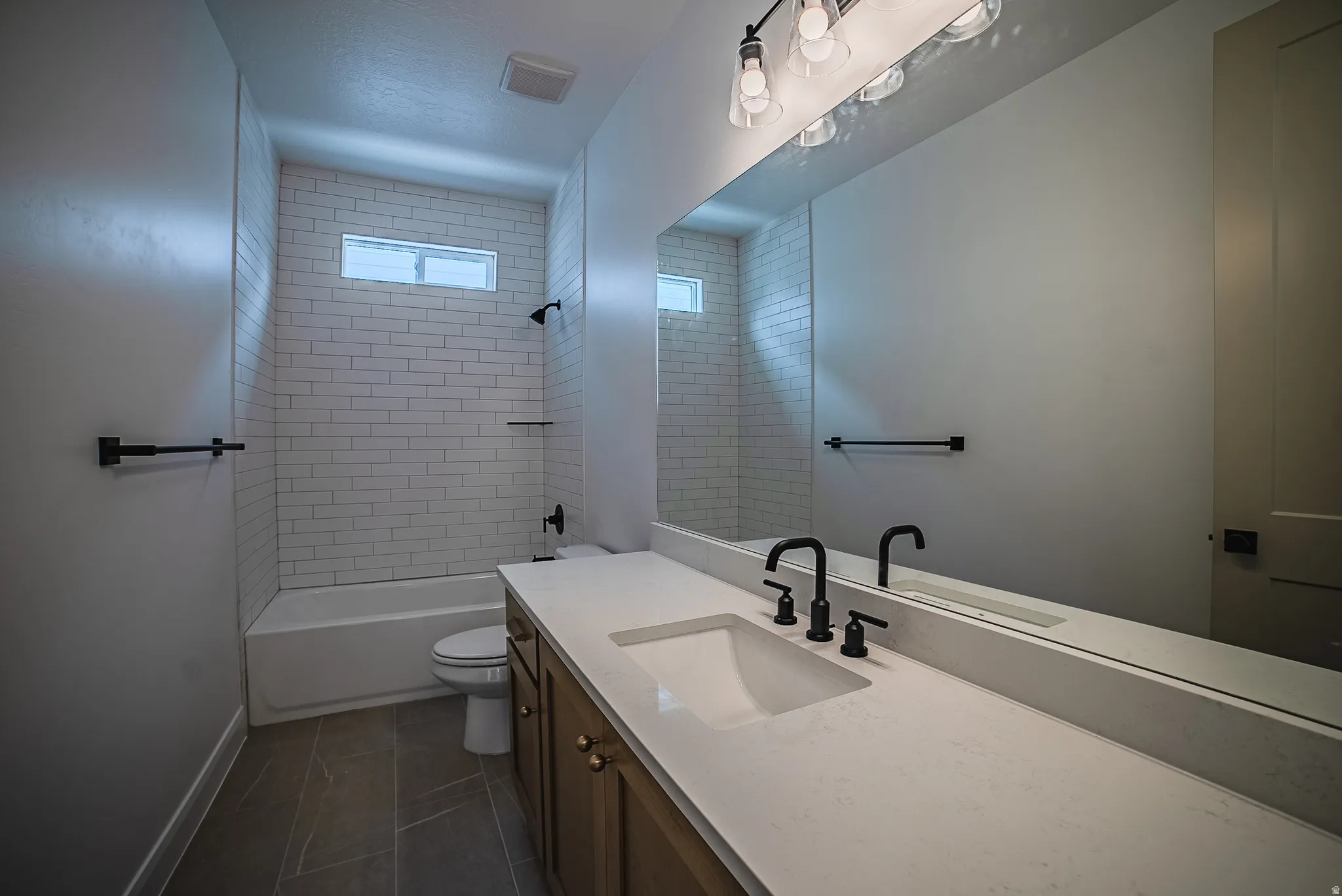 Bathroom featuring a light wood-finish vanity with a light countertop, integrated sink, and matte black fixtures