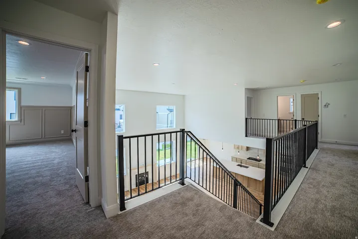 Upper-level landing with carpet flooring and black metal railings