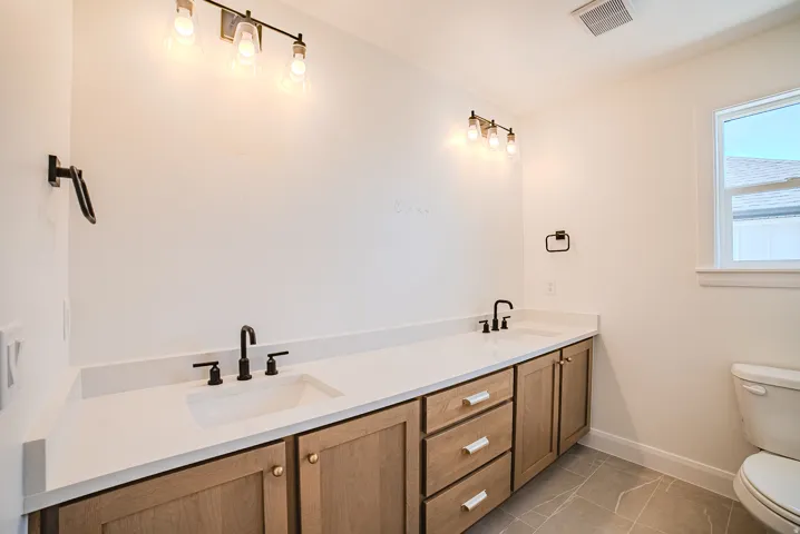 Dual vanity featuring light wood-finish cabinetry and white countertops