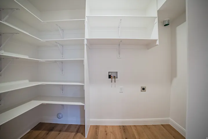 Utility area featuring white walls, wood-finish flooring, and white baseboards
