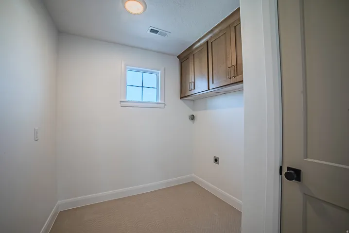 Dedicated utility space featuring overhead wood-finish cabinetry, a single window, recessed lighting, and herringbone pattern carpet flooring
