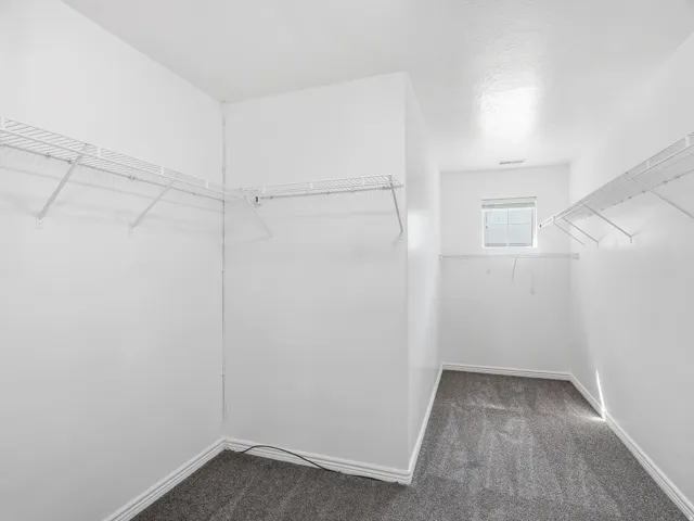 Huge walk-in closet featuring white wire shelving, and a window