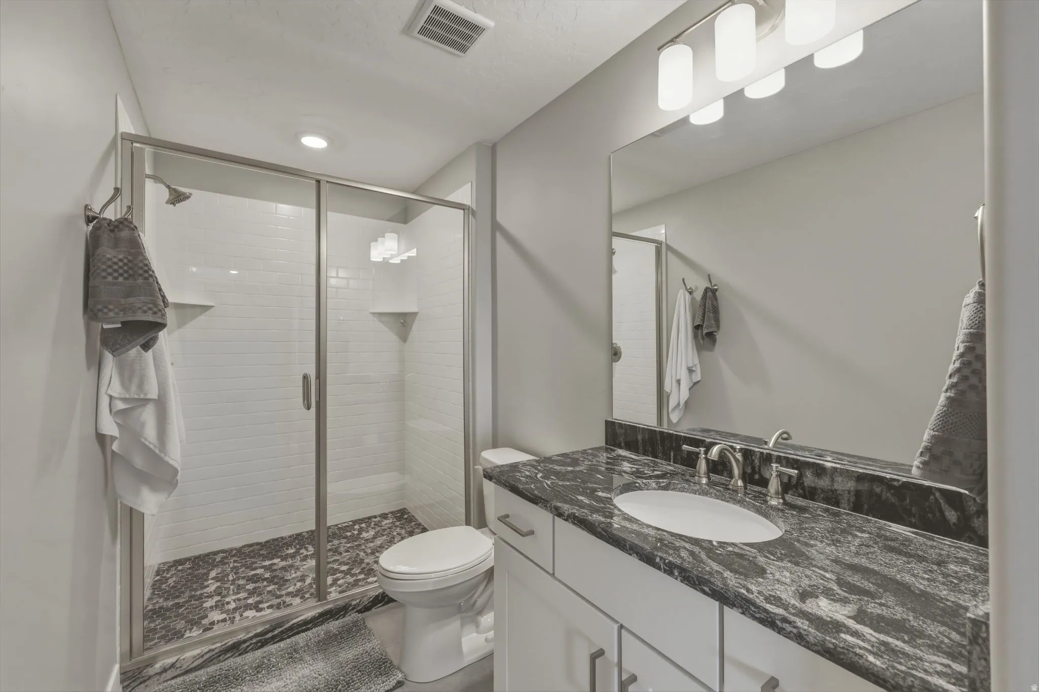 Bathroom attached to bedroom with granite countertops and walk in shower.