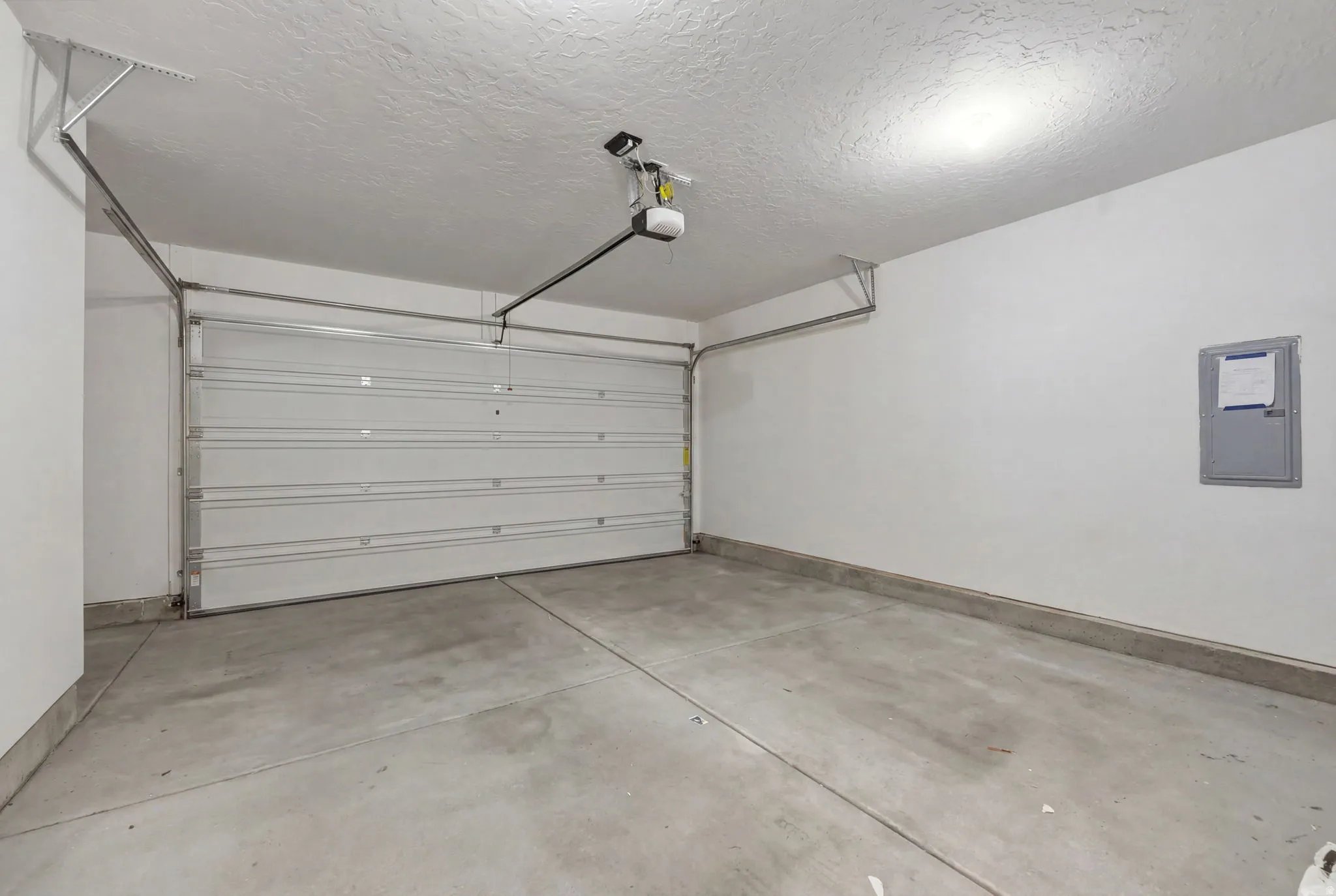 Attached garage featuring a concrete floor, white walls, and an automatic opener