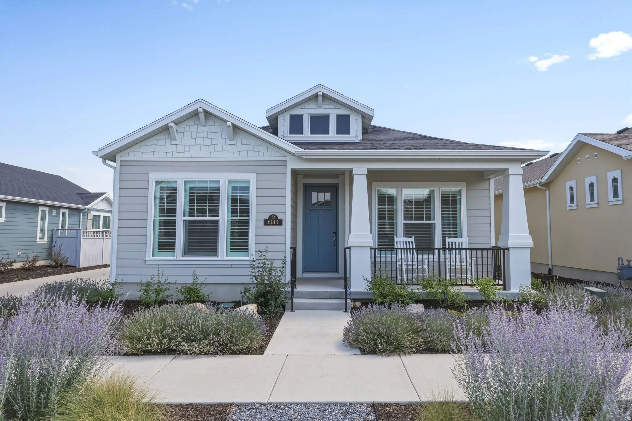Contemporary single-story residence featuring light gray siding with decorative shingle accents