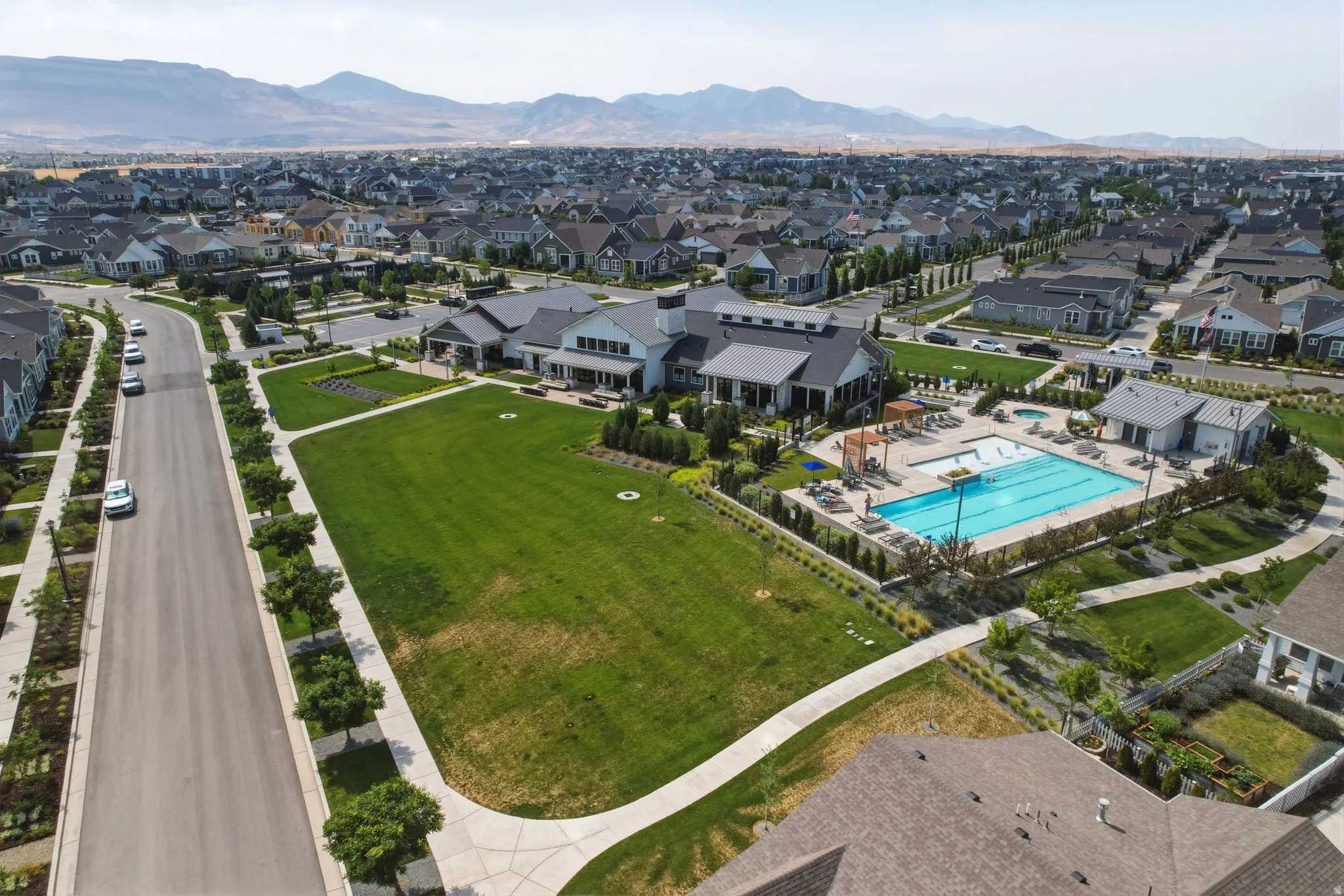Aerial perspective showcasing a community with extensive green space, a large swimming pool, and a clubhouse