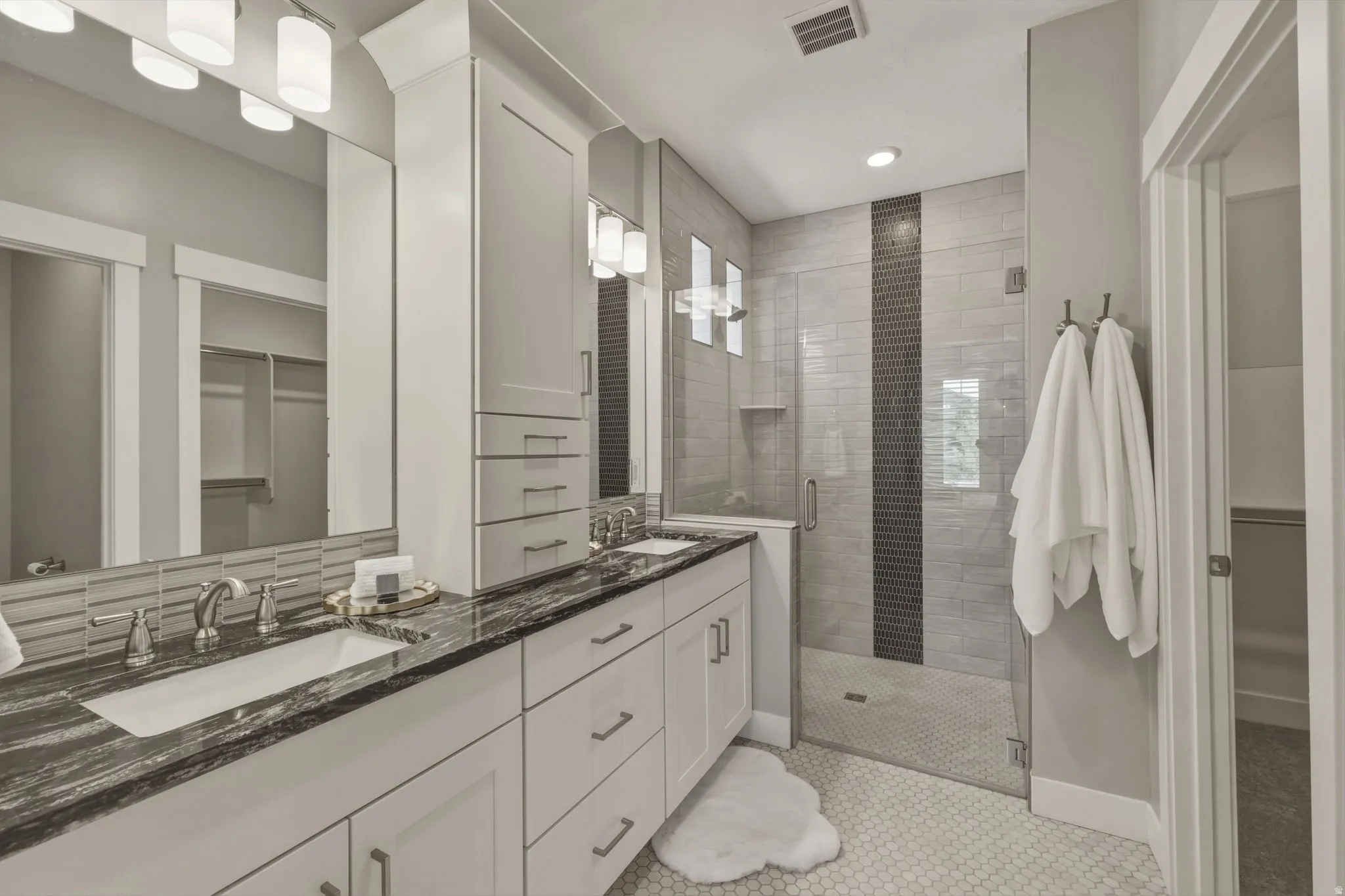 En suite bathroom with dual white rectangular under mount sinks set in granite  countertop.