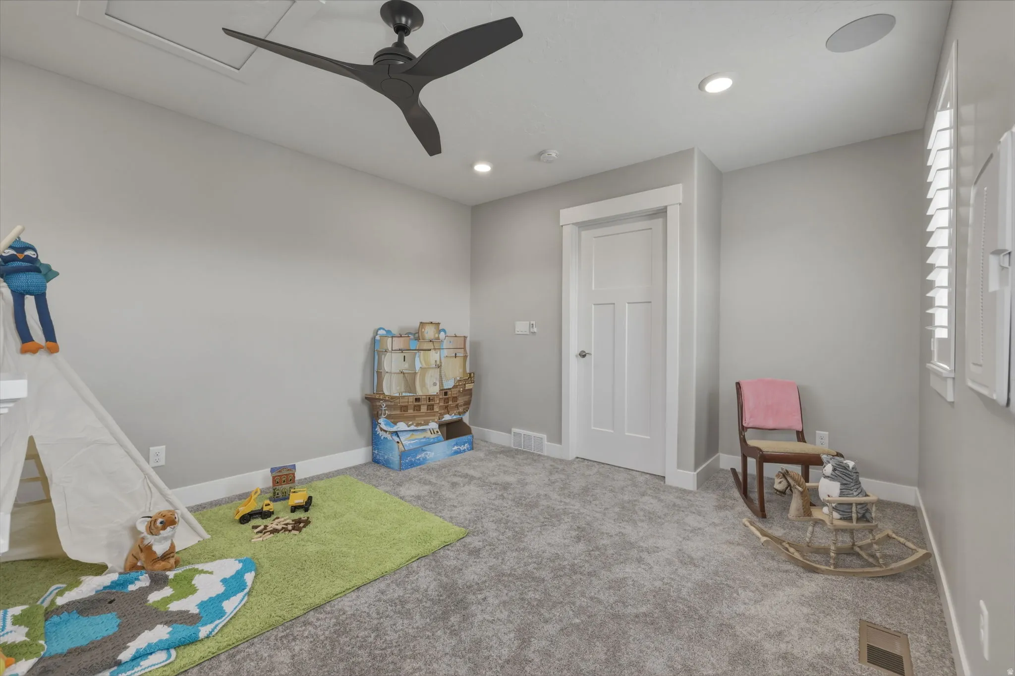 Room featuring gray carpet flooring and a ceiling fan.