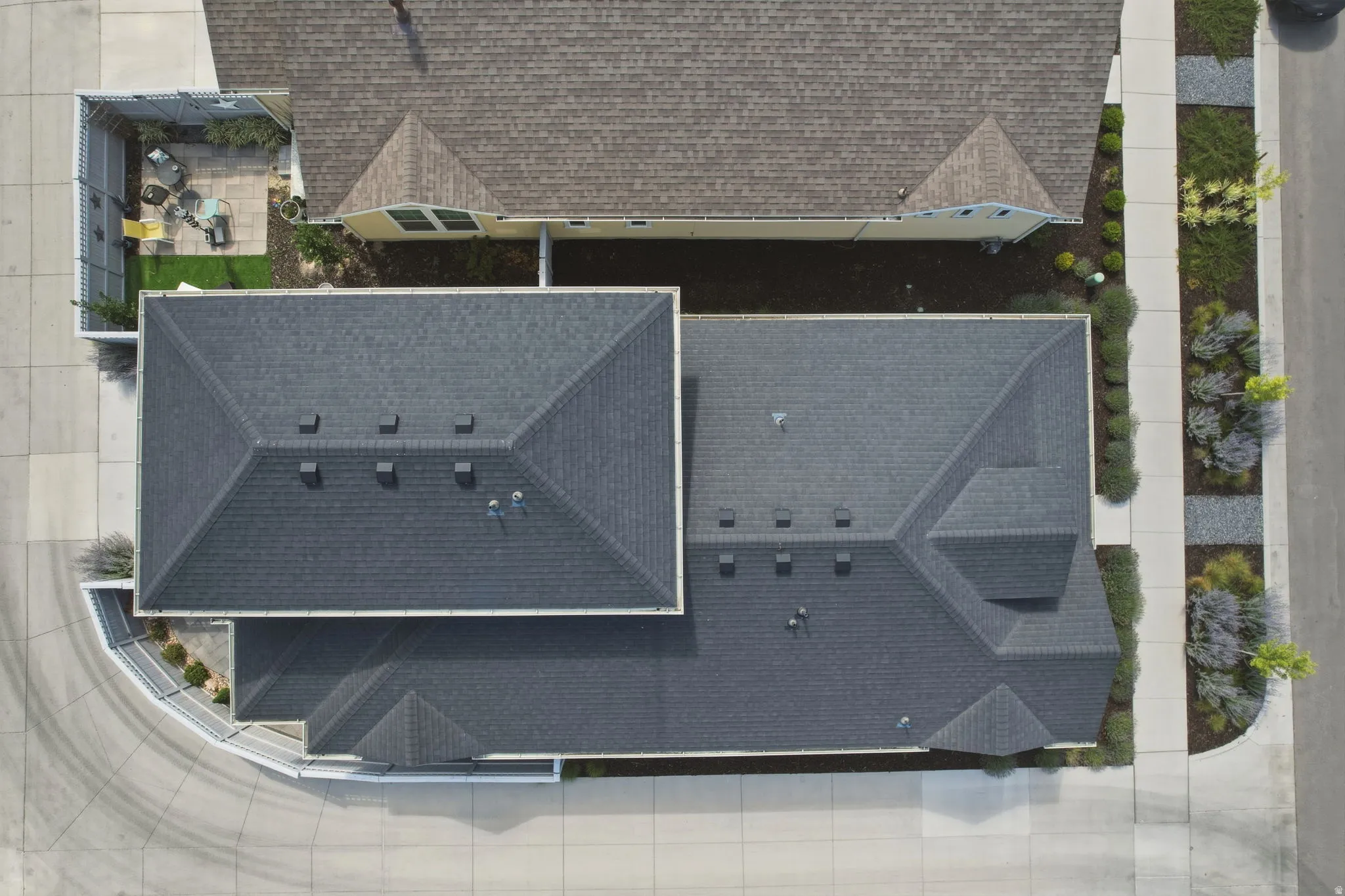 Property featuring a dark shingle roof, a paved driveway, and a private enclosed courtyard