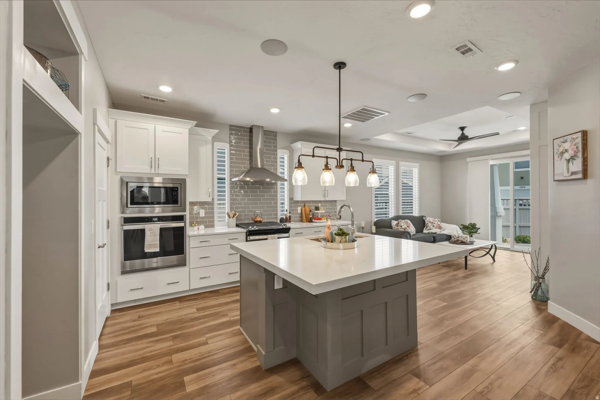 Spacious kitchen featuring an extra large island with quartz countertops, white cabinetry, stainless steel appliances, and LVP flooring