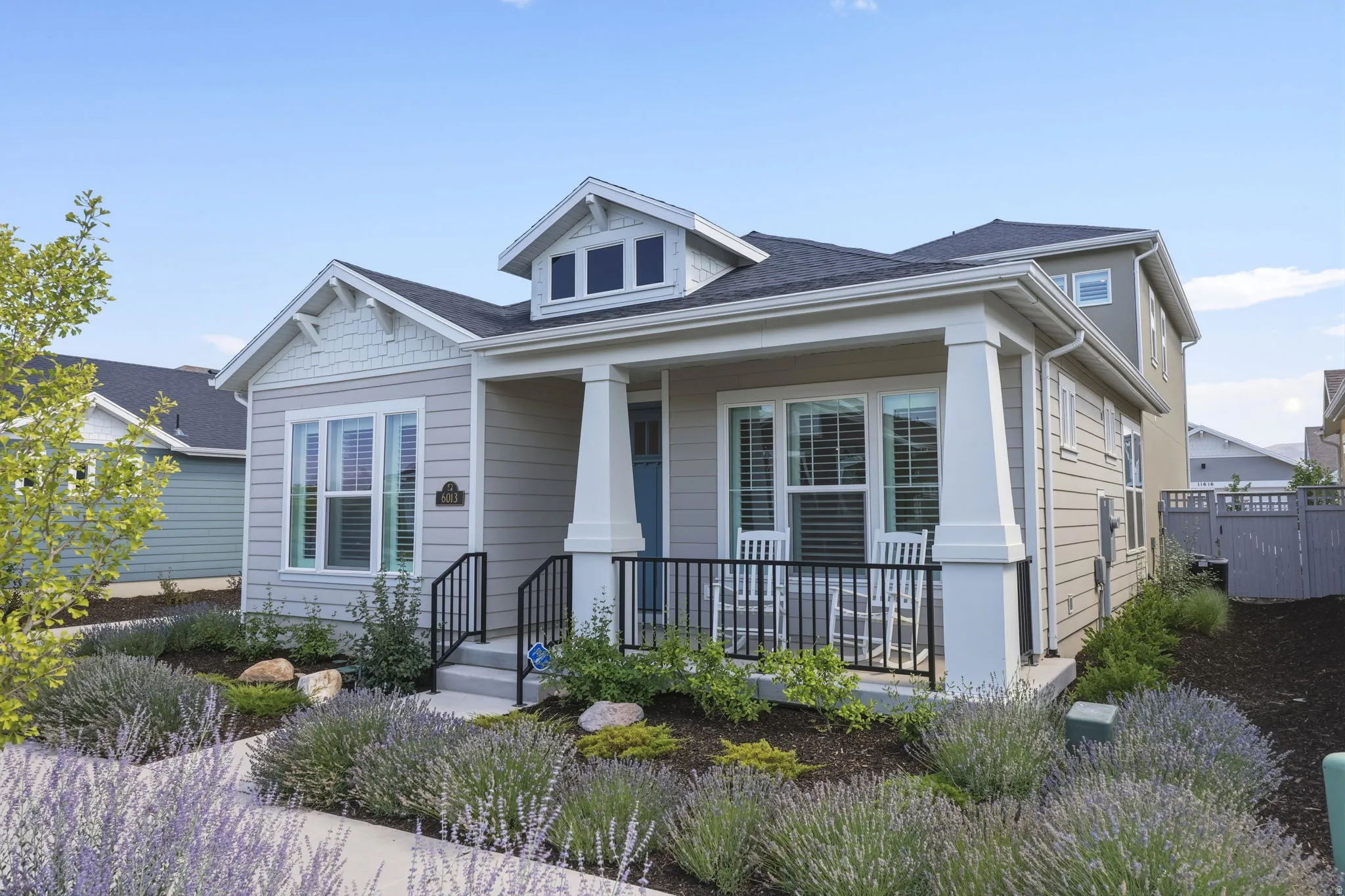 Light gray siding exterior with a covered front porch featuring white columns and black railings