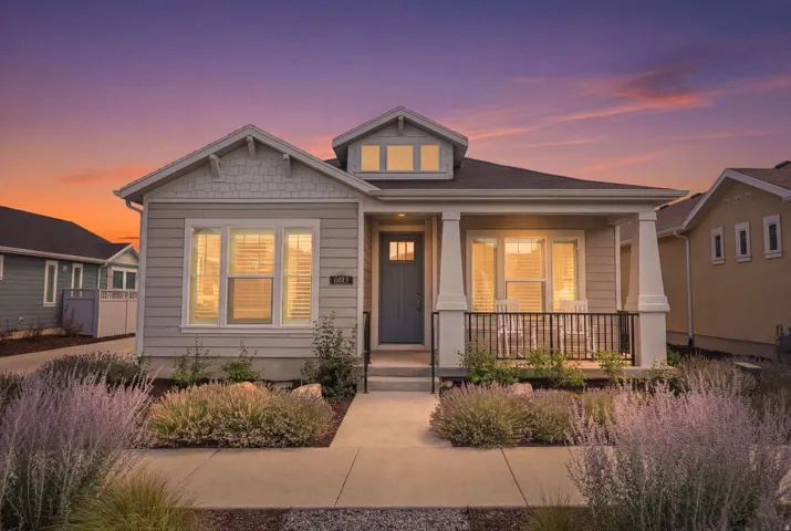 Exterior featuring light gray horizontal siding, white trim, a covered front porch with white columns, and a dark front door