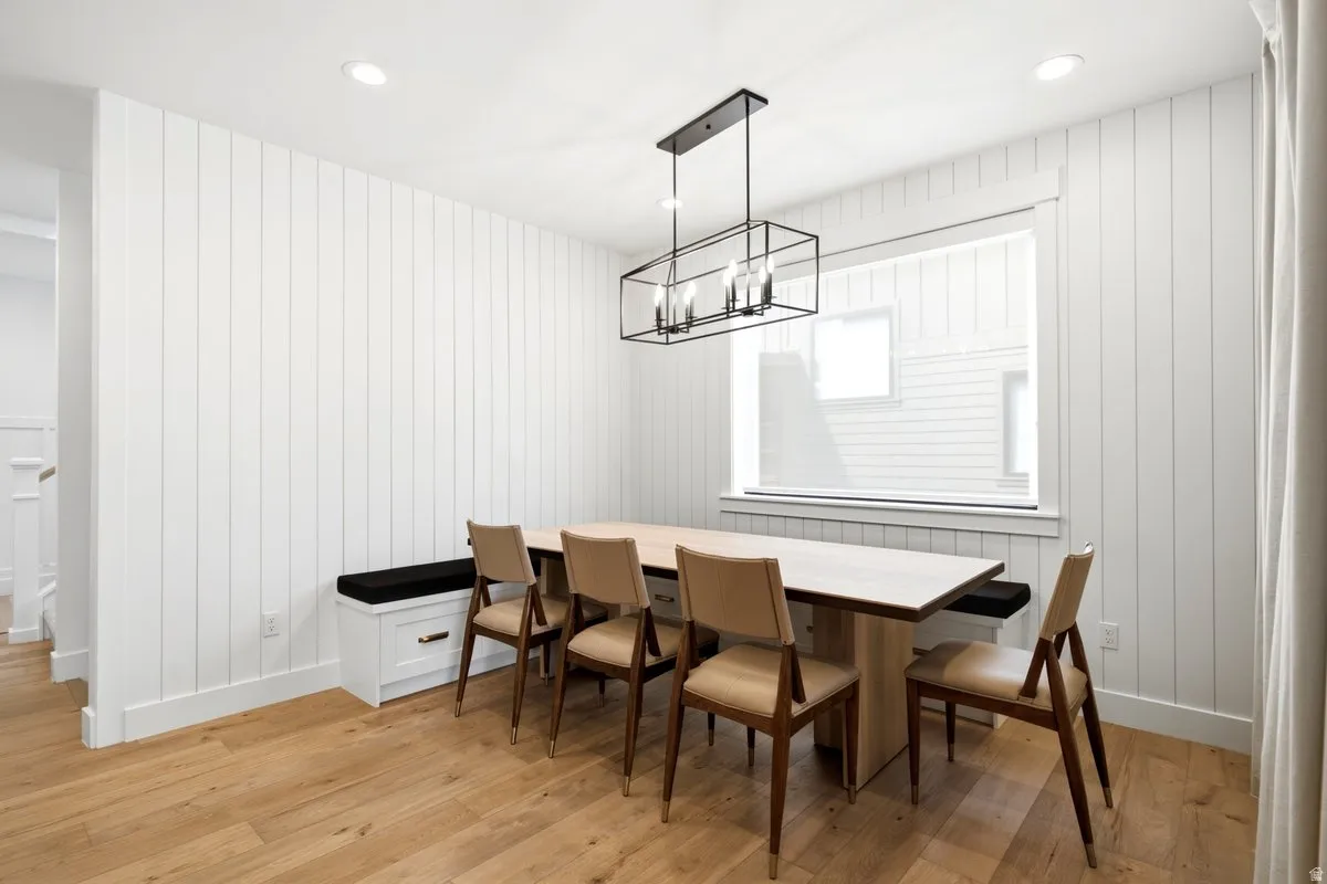 Dining area featuring white vertical shiplap paneling, wood-finish flooring, and recessed ceiling lighting
