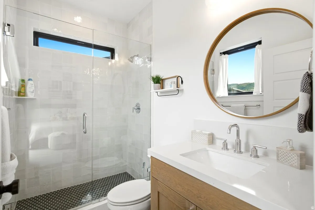 Contemporary bathroom featuring a spacious glass-enclosed shower with white subway tile surround and a black penny tile floor