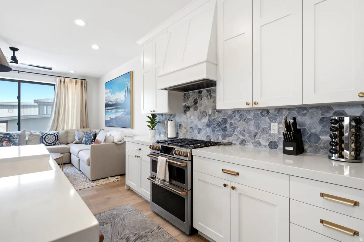 Contemporary kitchen featuring white cabinetry, light-toned countertops, and a hexagonal blue and gray tile backsplash