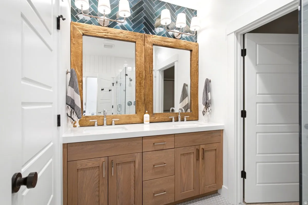 Double vanity featuring light wood-finish cabinetry, white countertops, and dual vessel sinks with chrome fixtures