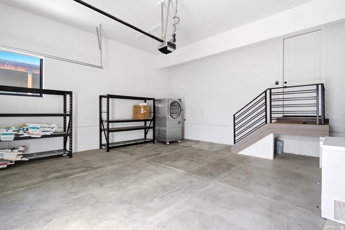 Concrete flooring garage space with a modern staircase featuring a black metal railing and wood-finish treads