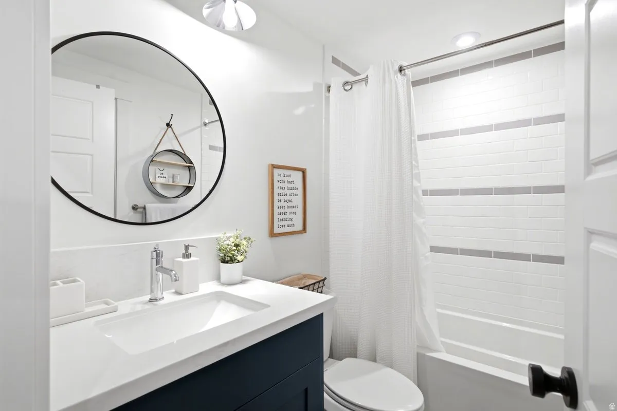 Contemporary bathroom featuring a dark blue vanity, integrated sink with chrome faucet, and a large circular mirror