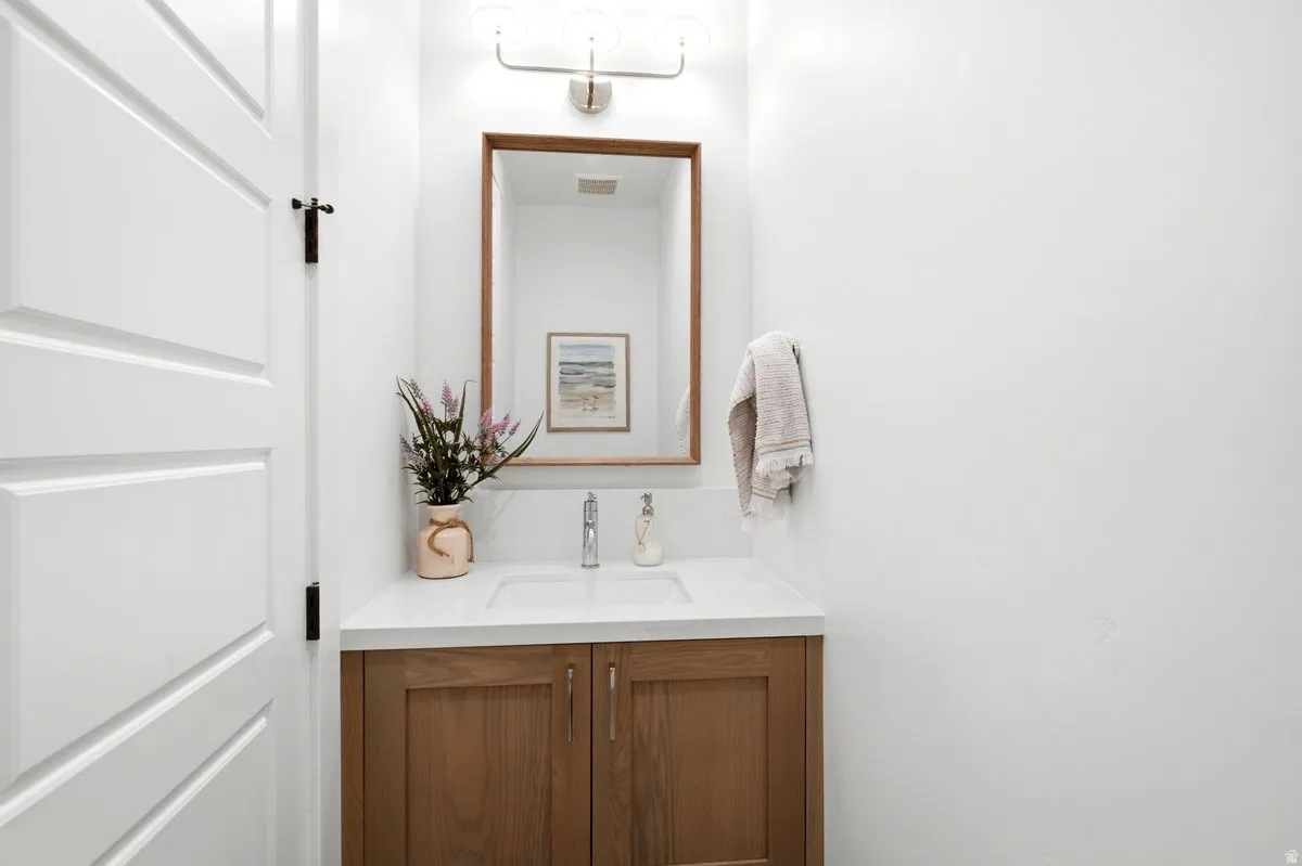 Bathroom vanity featuring a wood-finish cabinet, white countertop, and an integrated sink with a chrome faucet