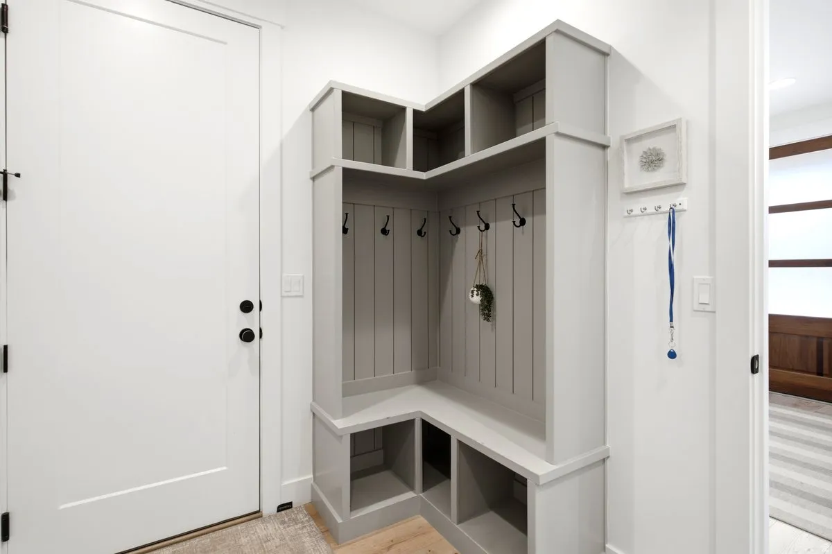 Built-in custom mudroom storage featuring a bench, shelving, and coat hooks