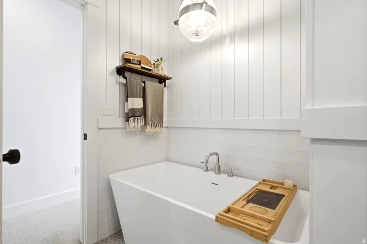 Freestanding soaking tub featuring a deck-mounted faucet with brushed nickel finish