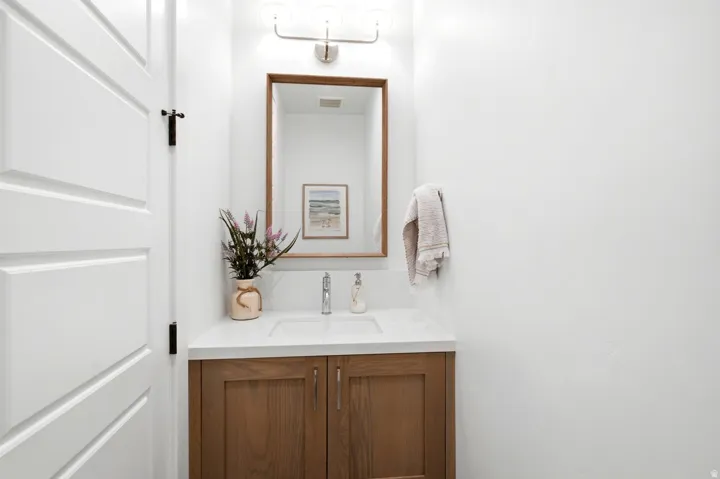 Bathroom vanity featuring a wood-finish cabinet, white countertop, and an integrated sink with a chrome faucet