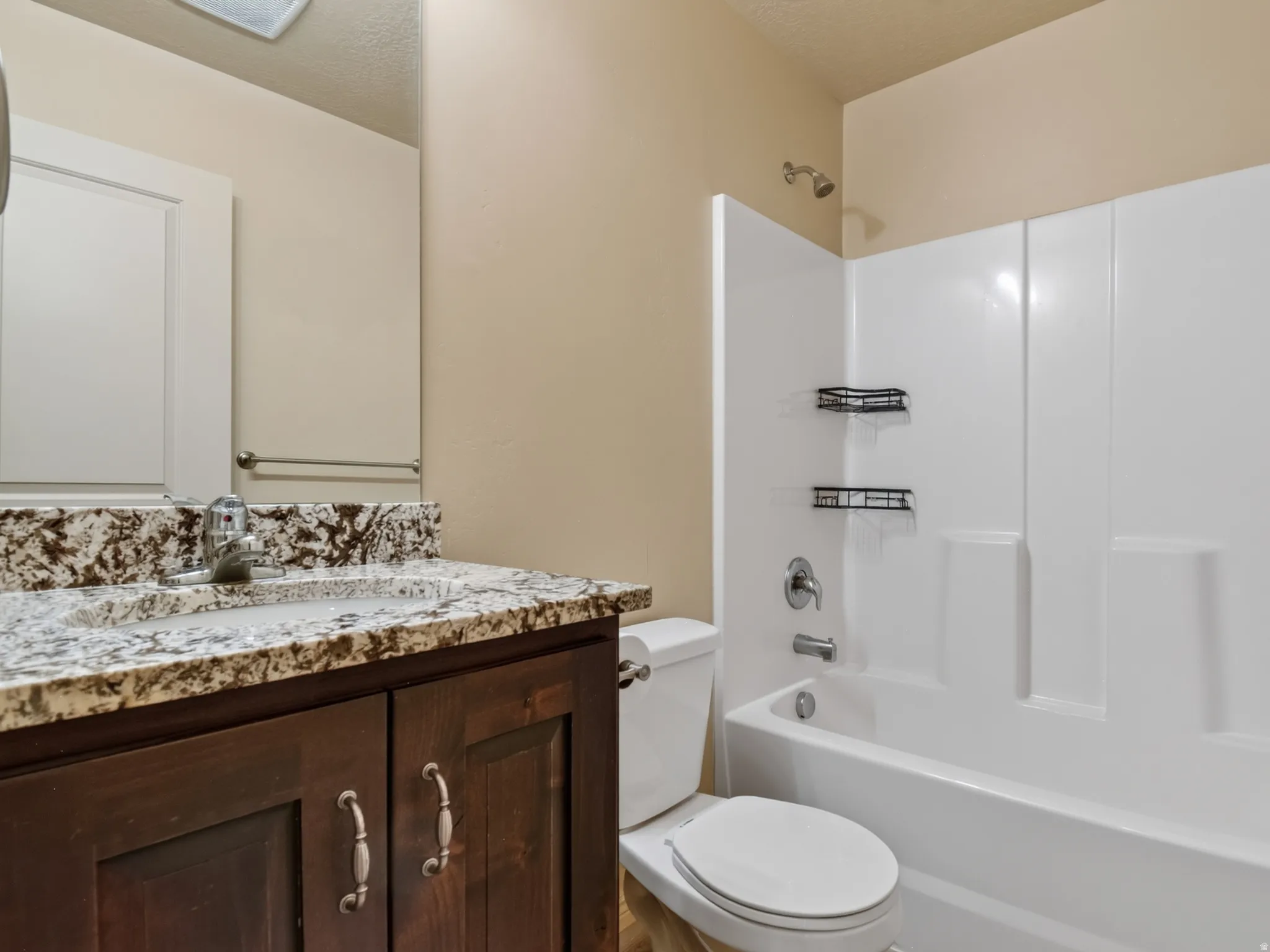 Bathroom vanity featuring a speckled countertop, undermount sink, and dark wood-finish cabinetry