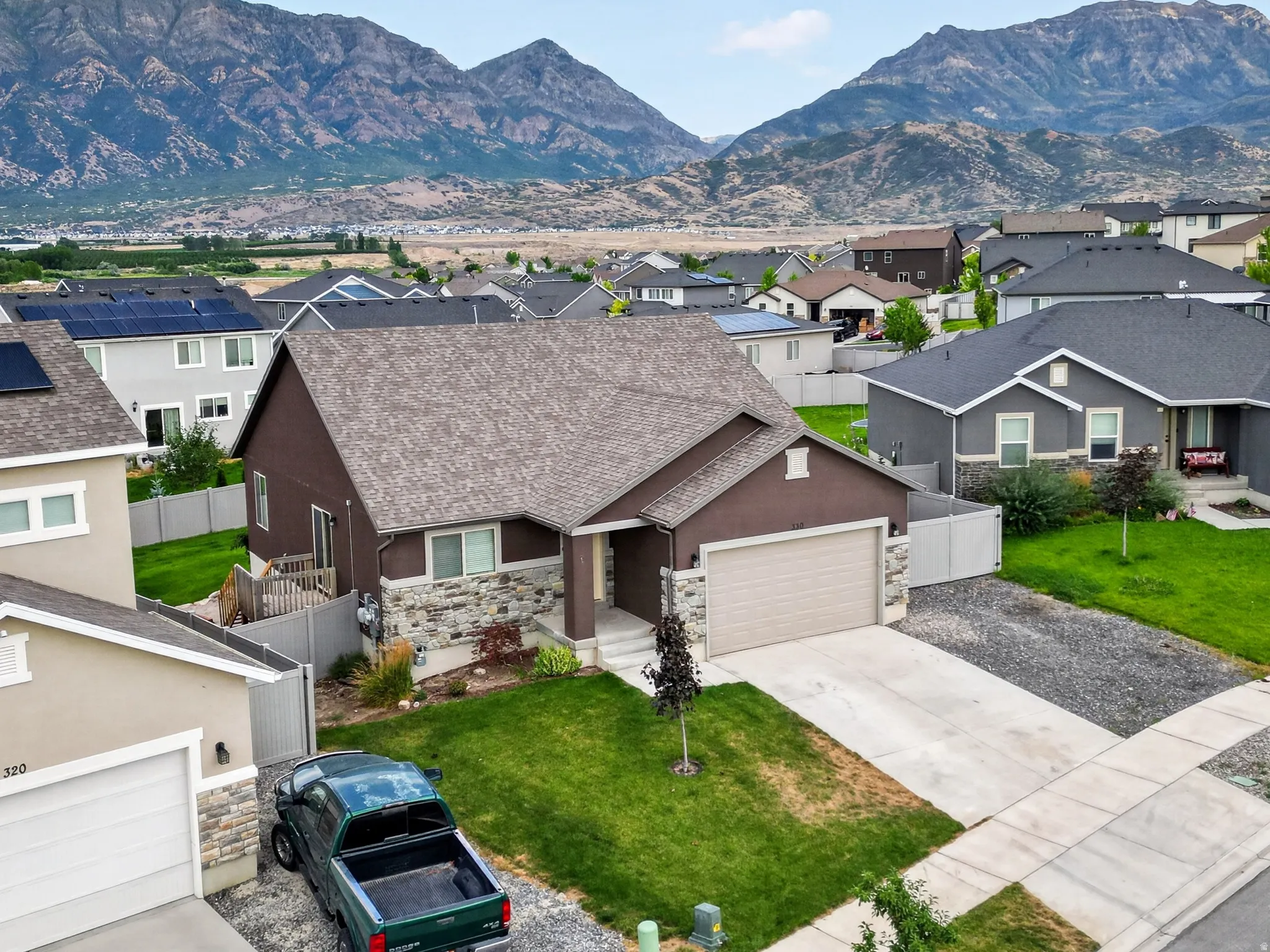 Single-story residence featuring a brown siding exterior with stone accents, a two-car garage, and a manicured front lawn