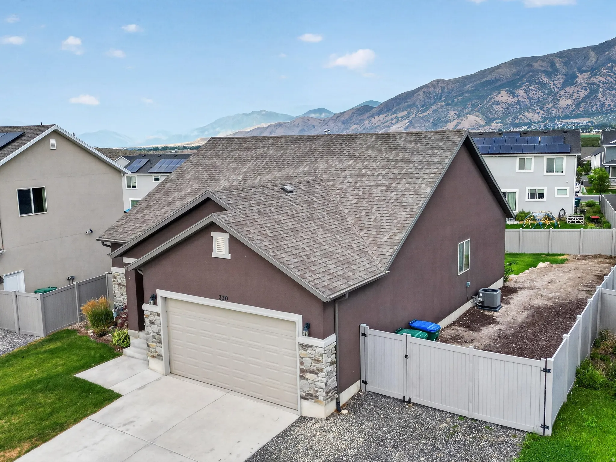 Contemporary stucco exterior with a stone veneer garage facade, featuring an attached two-car garage and a paved driveway