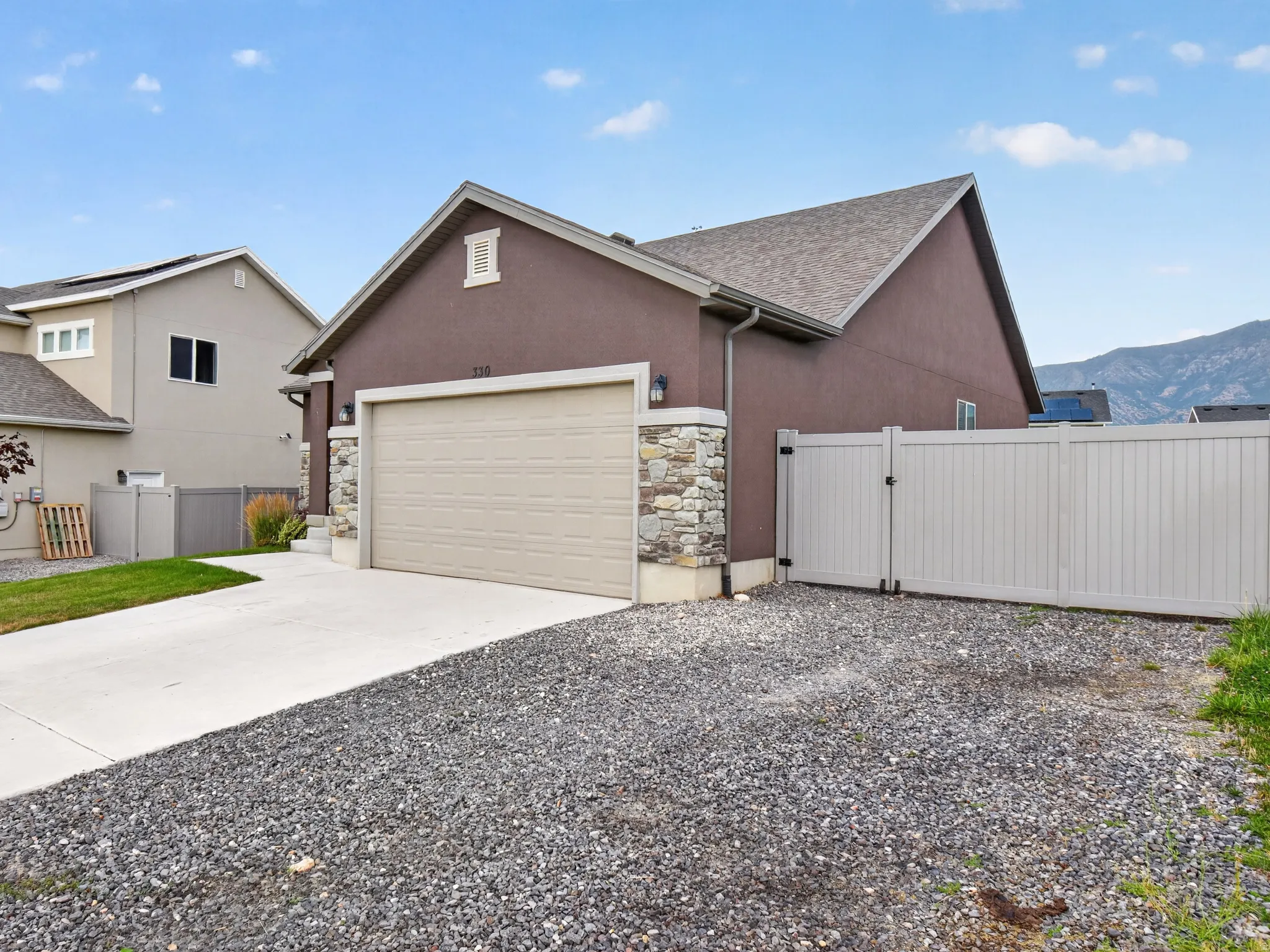 Stucco exterior featuring a stone accent column and a two-car garage