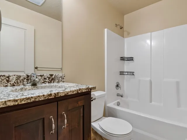 Bathroom vanity featuring a speckled countertop, undermount sink, and dark wood-finish cabinetry