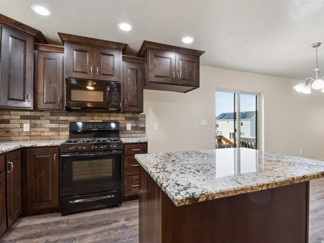 Kitchen featuring dark wood cabinetry, granite countertops, a tiled backsplash, and wood-finish flooring