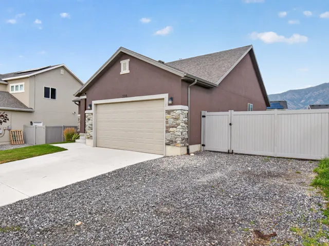 Stucco exterior featuring a stone accent column and a two-car garage