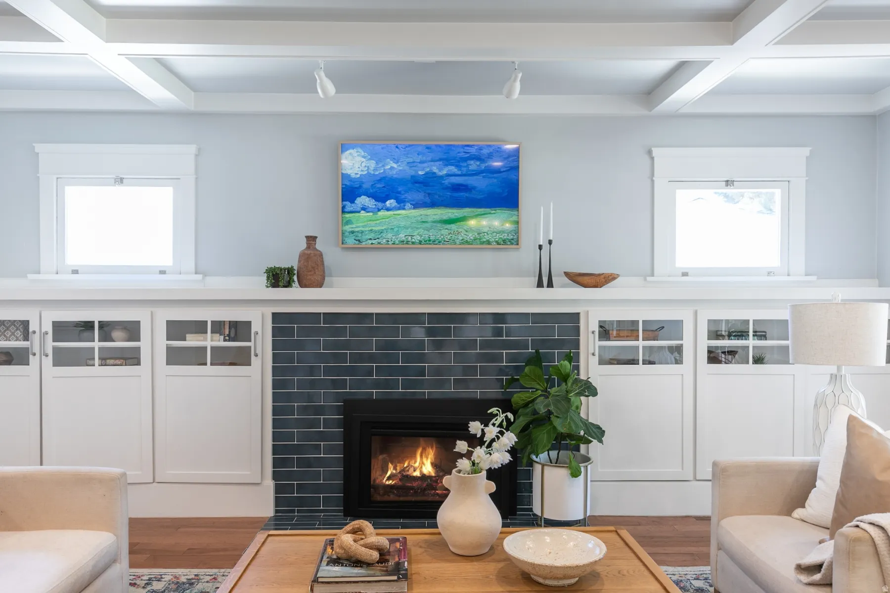 Built-in cabinetry with glass-front doors frames a fireplace featuring dark subway tile and a black firebox