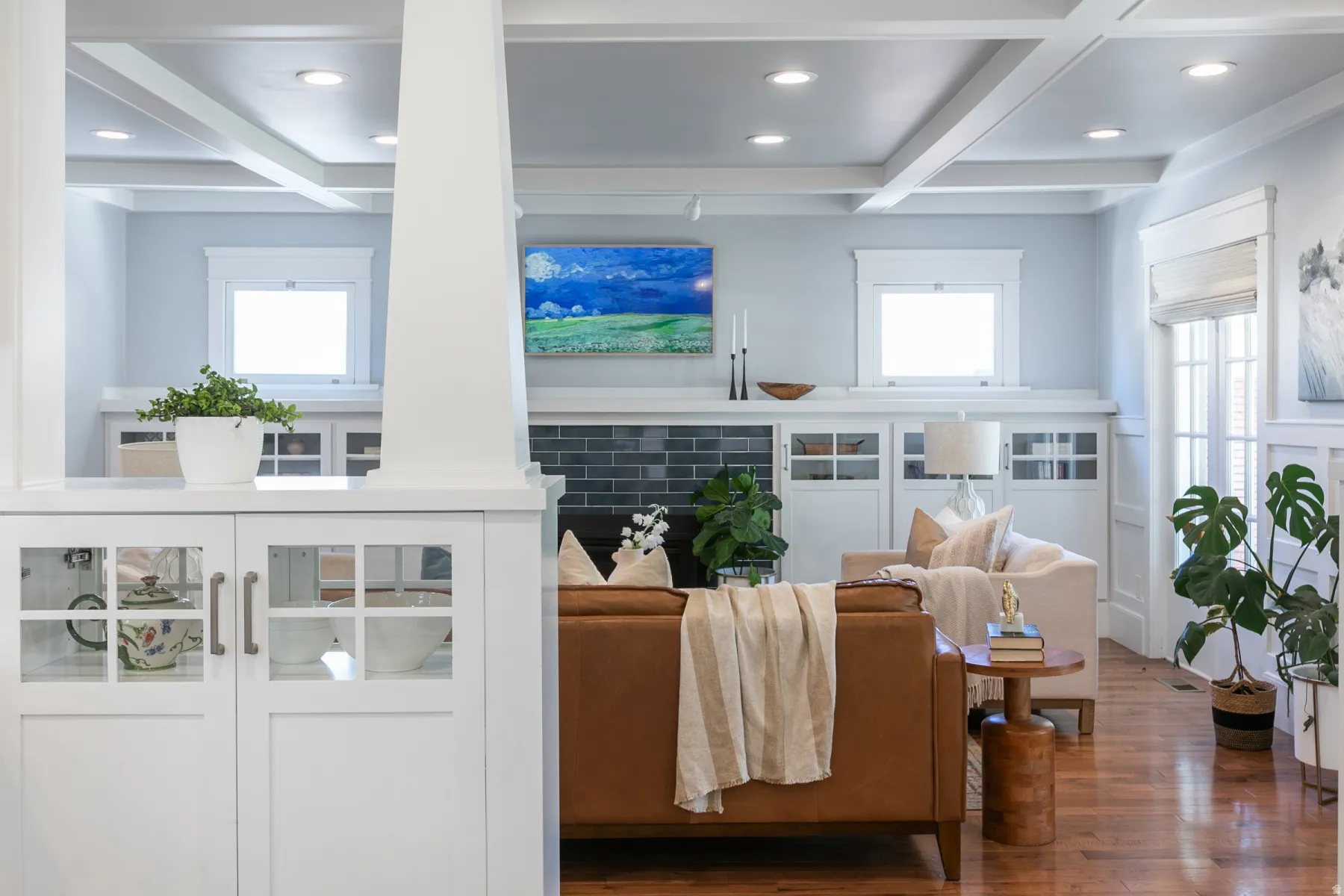 Living area featuring wood-finish flooring, a coffered ceiling with recessed lighting, and white built-in cabinetry with glass-paneled doors