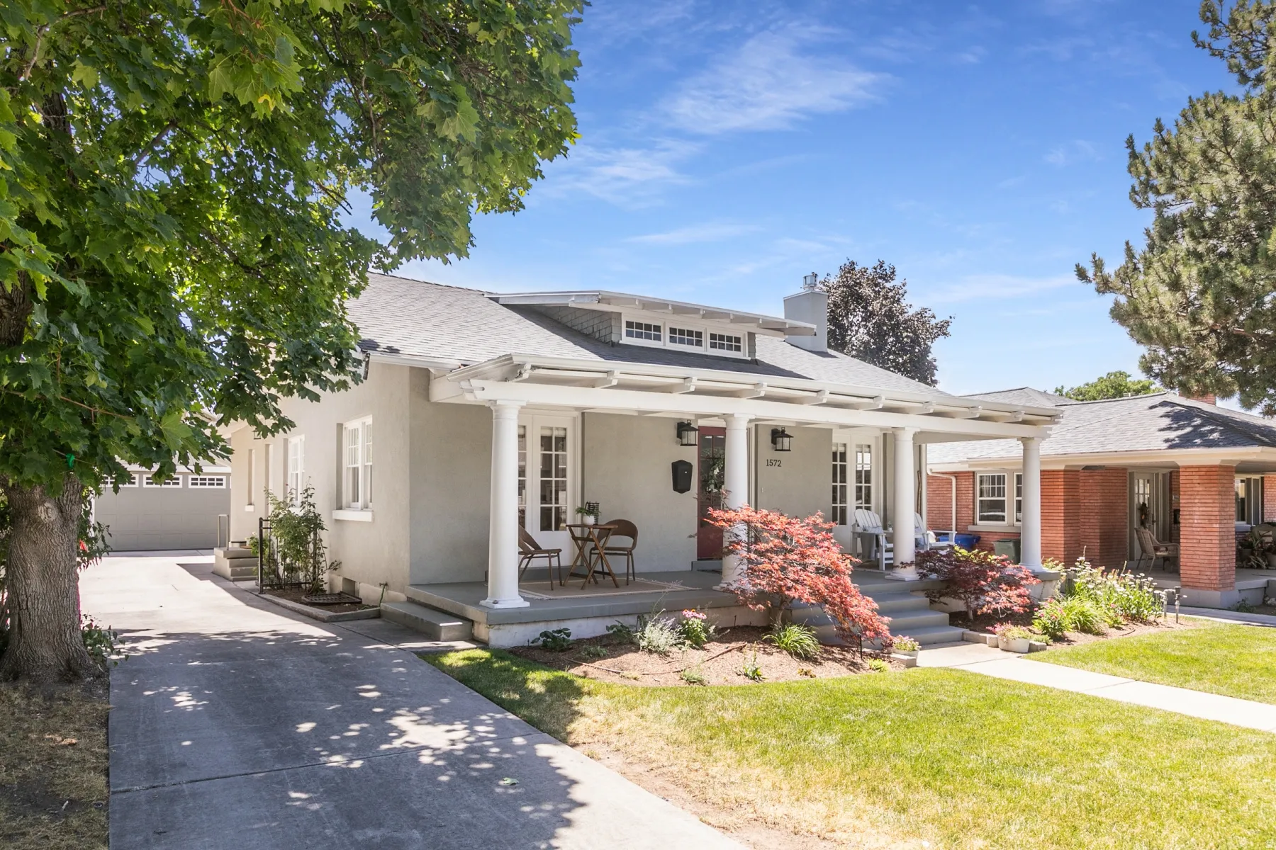 Inviting single-story residence featuring a covered front porch with white columns, a dormer with multiple windows, and a red front door