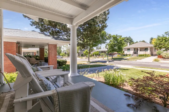 Covered front porch featuring white columns and a beadboard ceiling