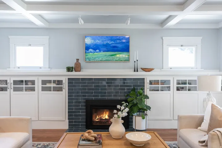 Built-in cabinetry with glass-front doors frames a fireplace featuring dark subway tile and a black firebox